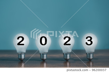 Turn On shine bright light bulb with 2023 Happy New Year on the desk and copy space for text decoration. 96200037