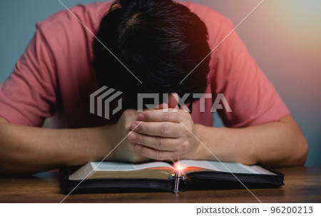 People holding hands head bow down pray to God in the middle book holy bible book with cross necklace front of the holy bible.. 96200213