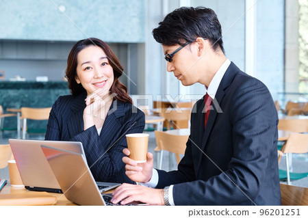 Male and female businessmen having a meeting while looking at a computer in a cafe 96201251