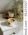 A bouquet of flowers, a cup of tea or coffee with milk and sweets on the table. Feels like home comfort and minimalism. aesthetic. 96203007