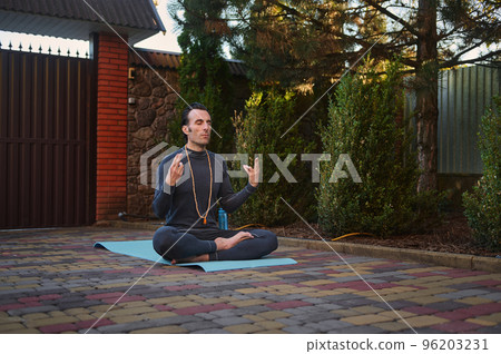 Middle aged Caucasian yogi during meditation outdoors. Yoga practice. Handsome athletic man sitting in lotus position, practicing yoga and breathing exercises at sunset. Taking a moment to breathe 96203231