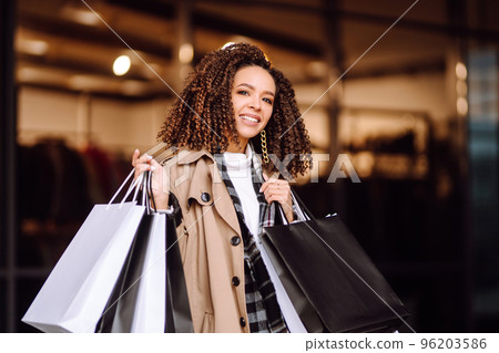 Stylish woman with shopping bags 'near mall. Young woman after shopping. Winter holidays. 96203586