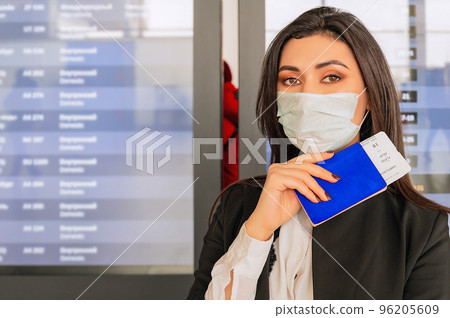 Girl with passport at the airport waits for a flight in front of airport desk Girl with passport at the airport waits for a flight in front of airport desk 96205609
