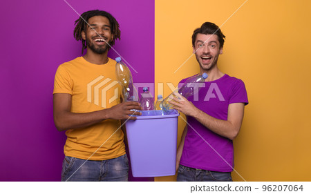 Friends hold a plastic container with bottles over yellow and purple color. Concept of ecology, conservation, recycling and sustainability Friends hold a plastic container with bottles over yellow and purple color. Concept of ecology, conservation, recycling and sustainability 96207064