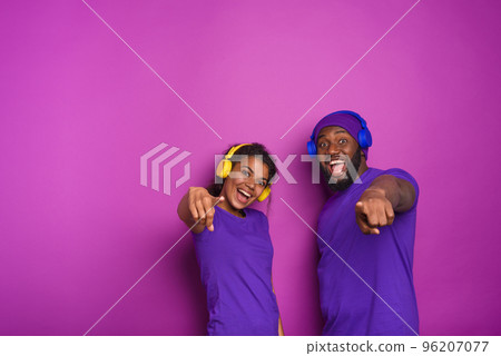 Couple with headset listen to music and have surprised expression. Purple background Couple with headset listen to music and have surprised expression. Purple background 96207077