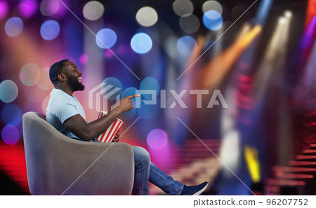 Man sitting on a armchair watches a show in a theatre Man sitting on a armchair watches a show in a theatre 96207752