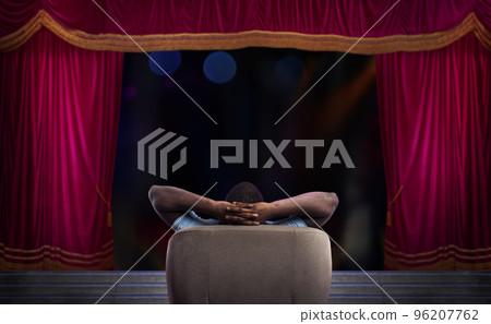 Man relaxing on a armchair and watches a show in a theatre 96207762