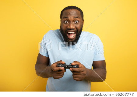 Happy man plays with a videogame on yellow background Happy man plays with a videogame on yellow background 96207777