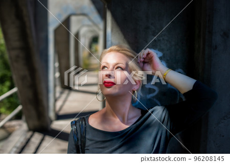 Pretty blonde woman portrait on a bridge in the shadows Pretty blonde woman portrait on a bridge in the shadows 96208145