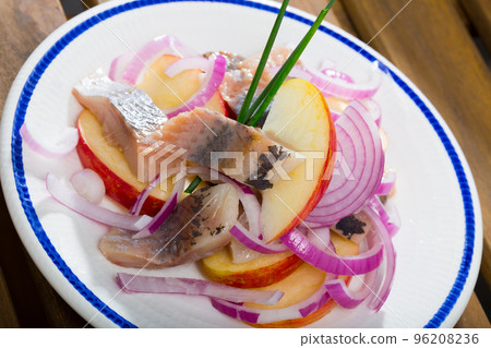 Fried potatoes with slices of mild-cured herring and onions on plate 96208236