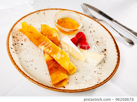 Traditional Russian dish - pancakes with honey, with two pieces of cheese and raspberries Traditional Russian dish - pancakes with honey, with two pieces of cheese and raspberries 96208678