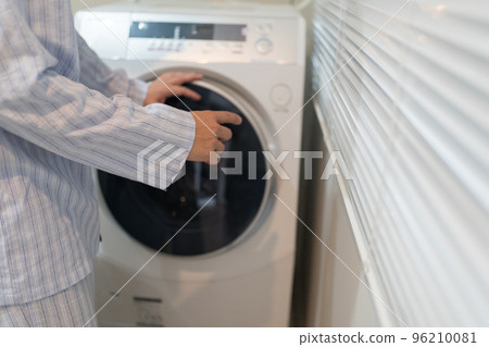 A man in his 40s in pajamas and a washing machine 96210081
