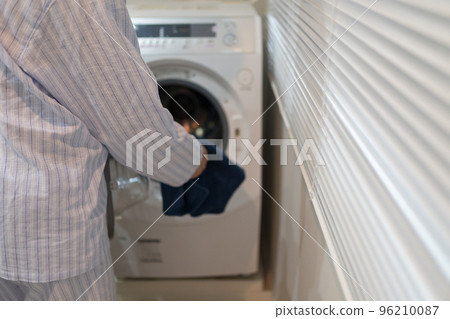 A man in his 40s in pajamas and a washing machine 96210087