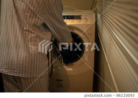 A man in his 40s in pajamas and a washing machine 96210093