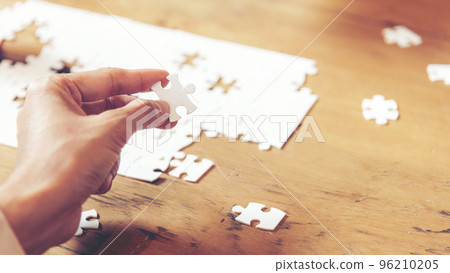 Close up Business people holding jigsaw connecting couple puzzle piece for matching to goals target.  96210205