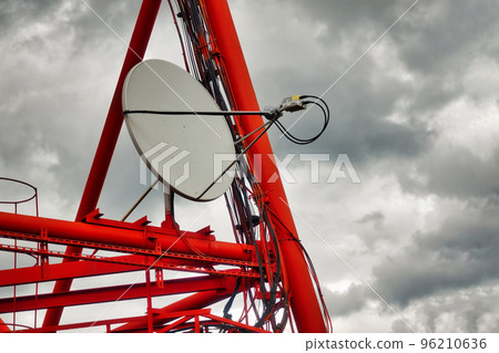 Part of communication tower with satellite dish against backdrop of dramatic sky with storm clouds. Telecommunication tower close-up. Part of communication tower with satellite dish against backdrop of dramatic sky with storm clouds. Telecommunication tower close-up. 96210636