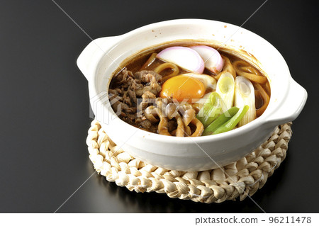 Miso-nikomi udon with beef, shimeji mushrooms, green onion, kamaboko, and egg yolk photographed against a black background Miso-nikomi udon with beef, shimeji mushrooms, green onion, kamaboko, and egg yolk photographed against a black background 96211478