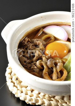 Miso-nikomi udon with beef, shimeji mushrooms, green onion, kamaboko, and egg yolk photographed against a black background Miso-nikomi udon with beef, shimeji mushrooms, green onion, kamaboko, and egg yolk photographed against a black background 96211486