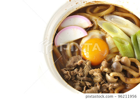Miso-nikomi udon with beef, shimeji mushrooms, green onions, kamaboko, and egg yolk is photographed from above with a white background. Miso-nikomi udon with beef, shimeji mushrooms, green onions, kamaboko, and egg yolk is photographed from above with a white background. 96211956