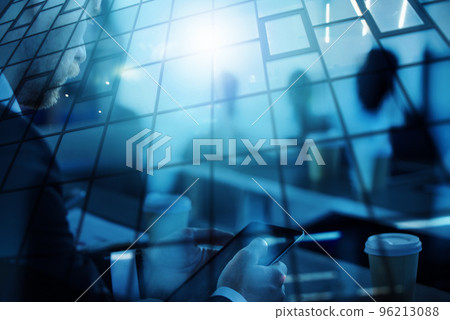Business man works in office with tablet in the foreground. Concept of teamwork and partnership. double exposure with light effects 96213088