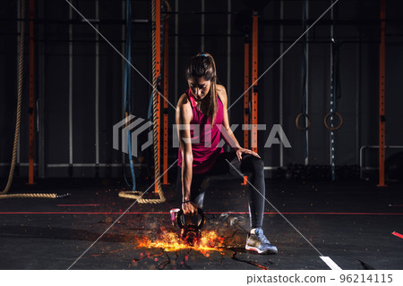 Athletic girl works out at the gym with a fiery kettlebell 96214115