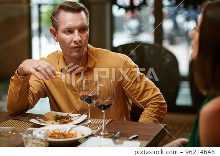 Man talking to wife when eating dinner in restaurant 96214646
