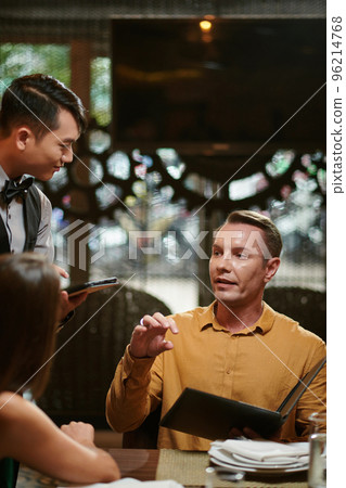 Man ordering food in restaurant for him and his family 96214768