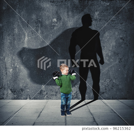Young child with his shadow of super hero on the wall. 96215362