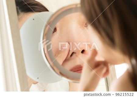 一個女人在鏡子裡看著她的鼻子 一個女人在鏡子裡看著她的鼻子 96215522
