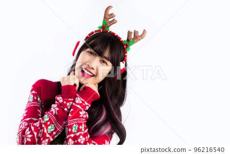 Pretty asian woman in christmas sweater costume reindeer horn headband and earmuffs posing white backgound. Pretty asian woman in christmas sweater costume reindeer horn headband and earmuffs posing white backgound. 96216540