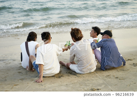 group of young asian adult men drinking beer clicking bottles toasting on beach, rear view 96216639