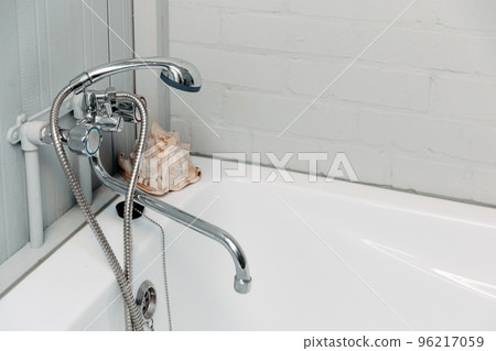 Bathroom with a shiny faucet, shower, white bathtub and a shell in the corner Bathroom with a shiny faucet, shower, white bathtub and a shell in the corner 96217059