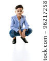 A 10-year-old Asian boy in a casual jacket is sitting smart and happy looking at the camera against a white isolate background. 96217258