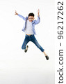 A 10-year-old Asian boy in a casual jacket is jumping smartly and happily looking at the camera against a white isolate background. 96217262