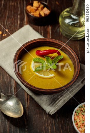 Turkish soup of chickpeas and lentils, with the addition of hot red pepper, lemon and mint. Close-up on a dark wooden background., vertical 96218450