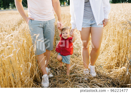 Healthy mother, father and little son enjoy nature together in the fresh air. A happy family with a child walks through a wheat field by the hands Healthy mother, father and little son enjoy nature together in the fresh air. A happy family with a child walks through a wheat field by the hands 96221477