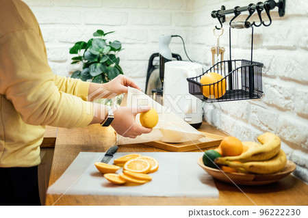 How to Dry Orange Slices for Holiday Decor. Process of Drying Orange Slices in the Oven. Woman cutting slices of orange and citrus fruits for drying in oven in home kitchen 96222230