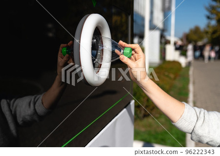 Woman uses a self service machine to receive used plastic bottles 96222343