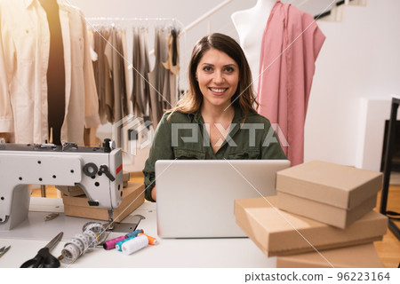 Seamstress works to new clothes ordered by internet client Seamstress works to new clothes ordered by internet client 96223164