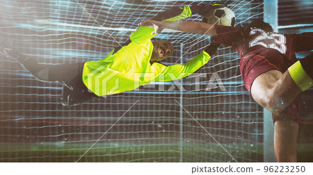 Soccer goalkeeper, in fluorescent uniform, makes a save on a close head shot of the attacker 96223250