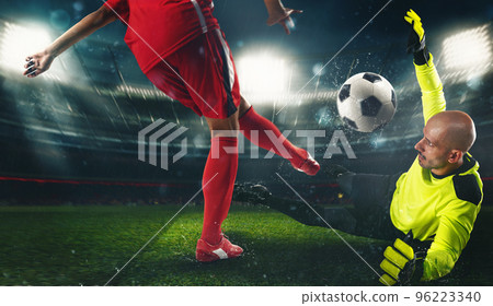 Soccer goalkeeper, in fluorescent uniform, countering the attacker in red uniform 96223340