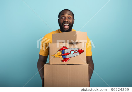 Happy man holds a lot of received packages. Cyan background Happy man holds a lot of received packages. Cyan background 96224269