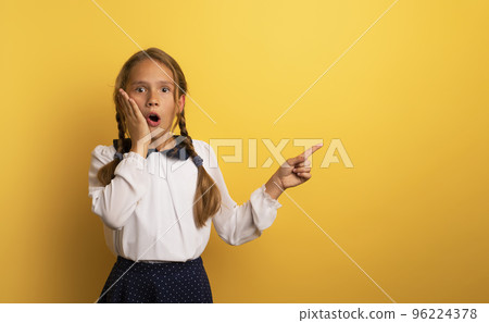 Young student is with shocked expression and indicates something. Yellow background. Young student is with shocked expression and indicates something. Yellow background. 96224378
