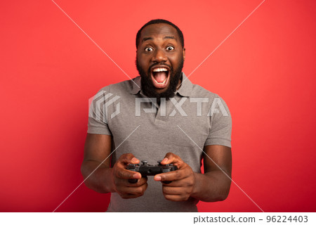 Happy man plays with a videogame on red background 96224403