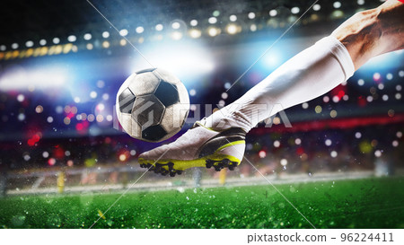 Football scene at night match with close up of a soccer shoe hitting the ball with power 96224411