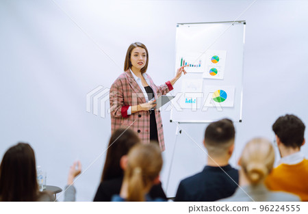Young woman coach speaker giving flipchart presentation, speaker leading training Young woman coach speaker giving flipchart presentation, speaker leading training 96224555