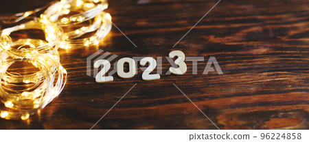 wooden number 2023 on christmas shiny wooden background. with sparkle festive gold garland 96224858