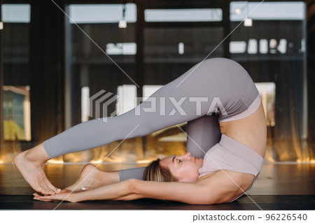 The girl does yoga. A woman in sports clothes does yoga exercises in the gym The girl does yoga. A woman in sports clothes does yoga exercises in the gym 96226540