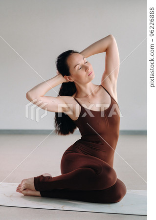 a woman in a brown suit does yoga in a fitness room . Healthy lifestyle, fitness, training, self-care a woman in a brown suit does yoga in a fitness room . Healthy lifestyle, fitness, training, self-care 96226888