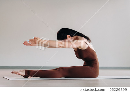 a woman in a brown suit does yoga in a fitness room . Healthy lifestyle, fitness, training, self-care 96226899